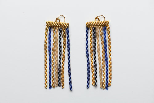 Pair of gold and blue beaded earrings on a light gray background
