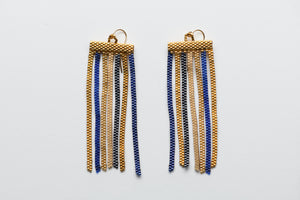 Pair of gold and blue beaded earrings on a light gray background