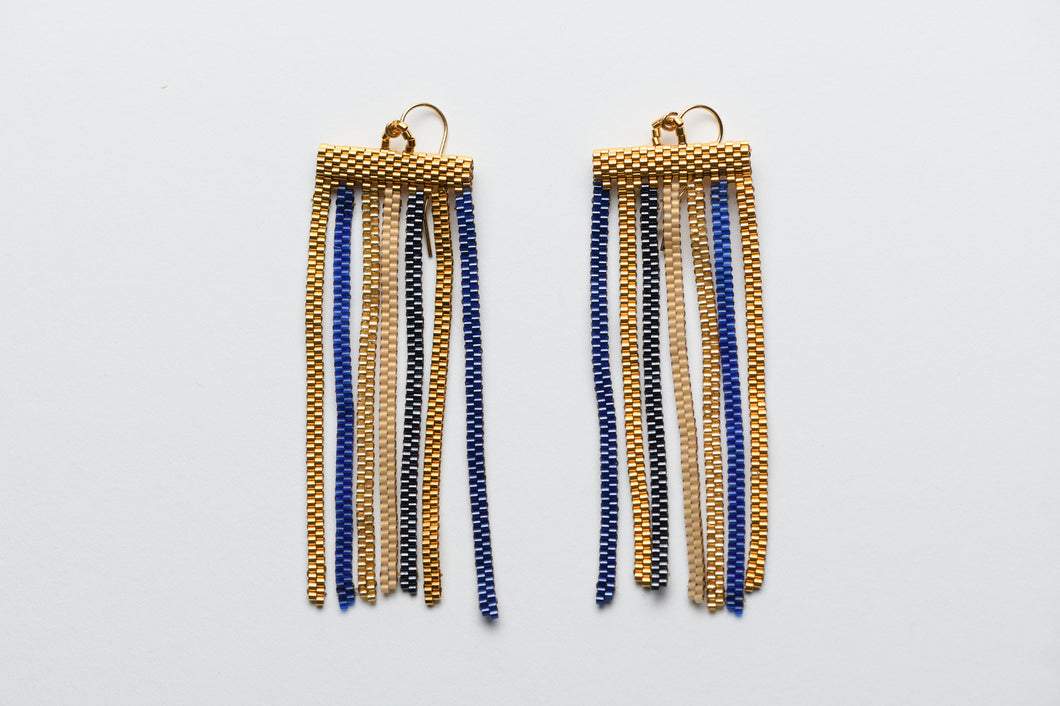 Pair of gold and blue beaded earrings on a light gray background